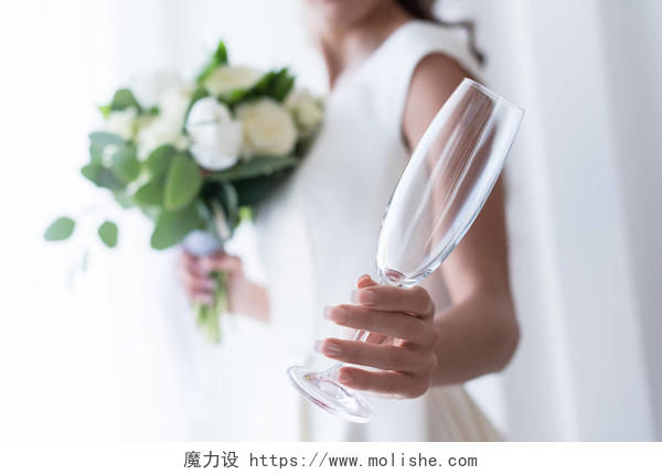 焦点在新娘与婚礼花束和持有空香槟玻璃